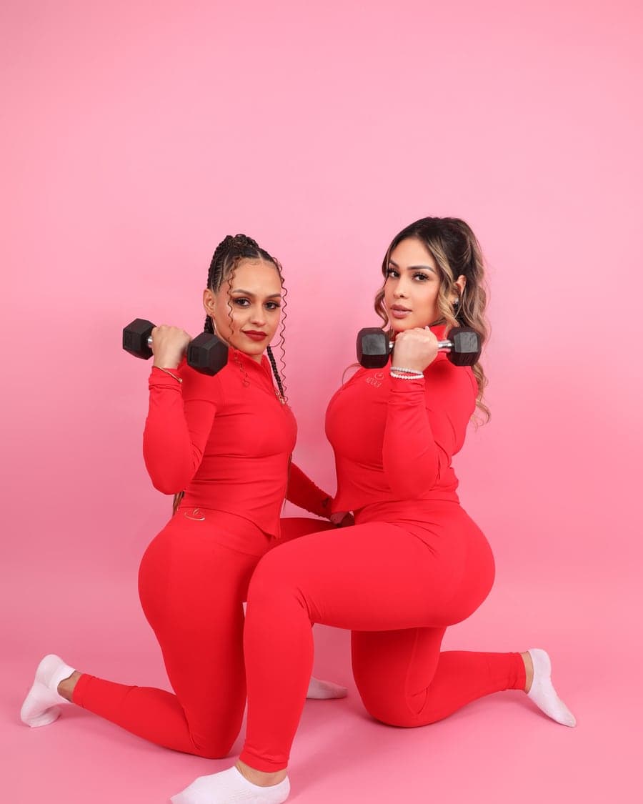 Two women in the AEVAH red sets with dumbbells