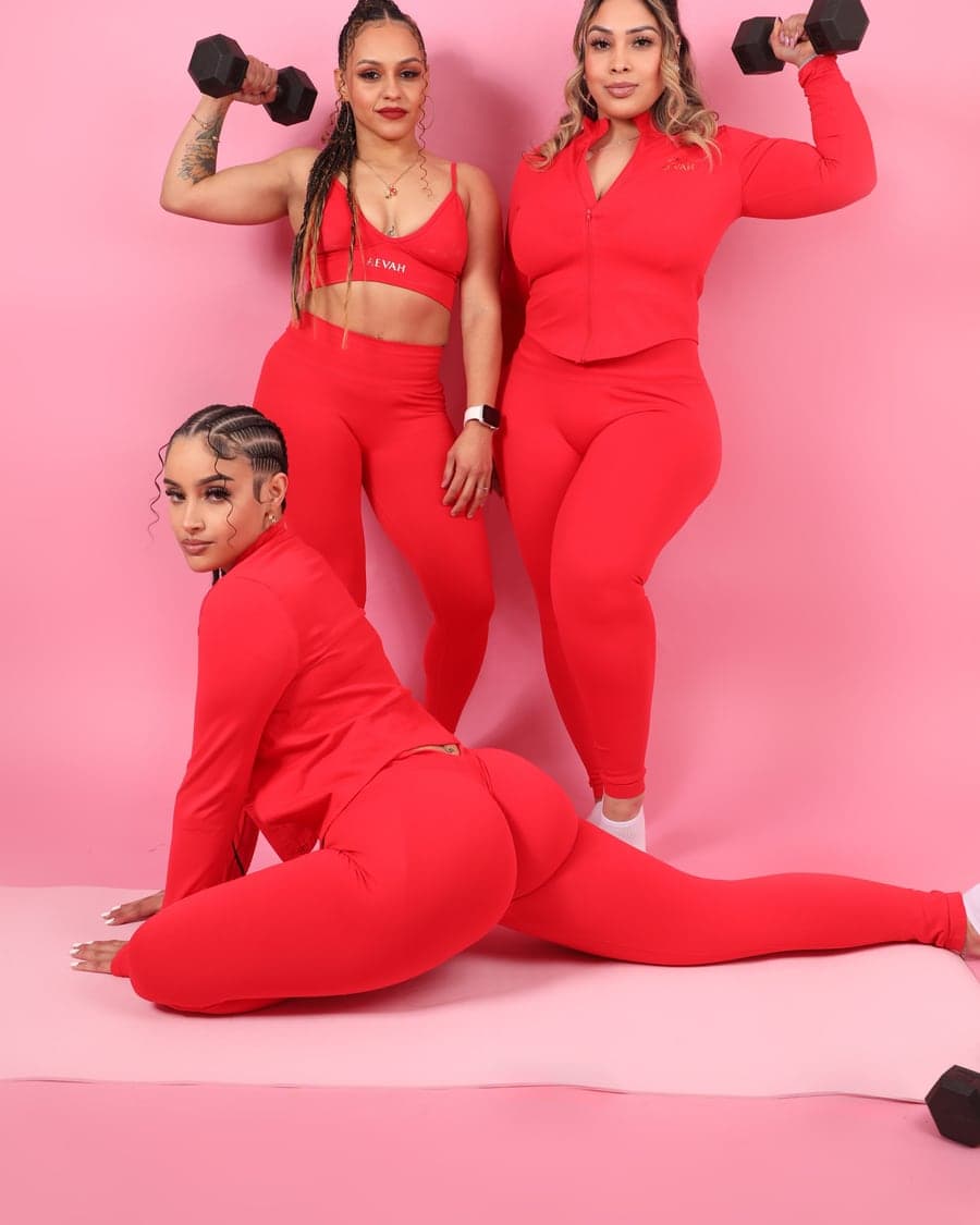 Three women in the AEVAH red sets with dumbbells
